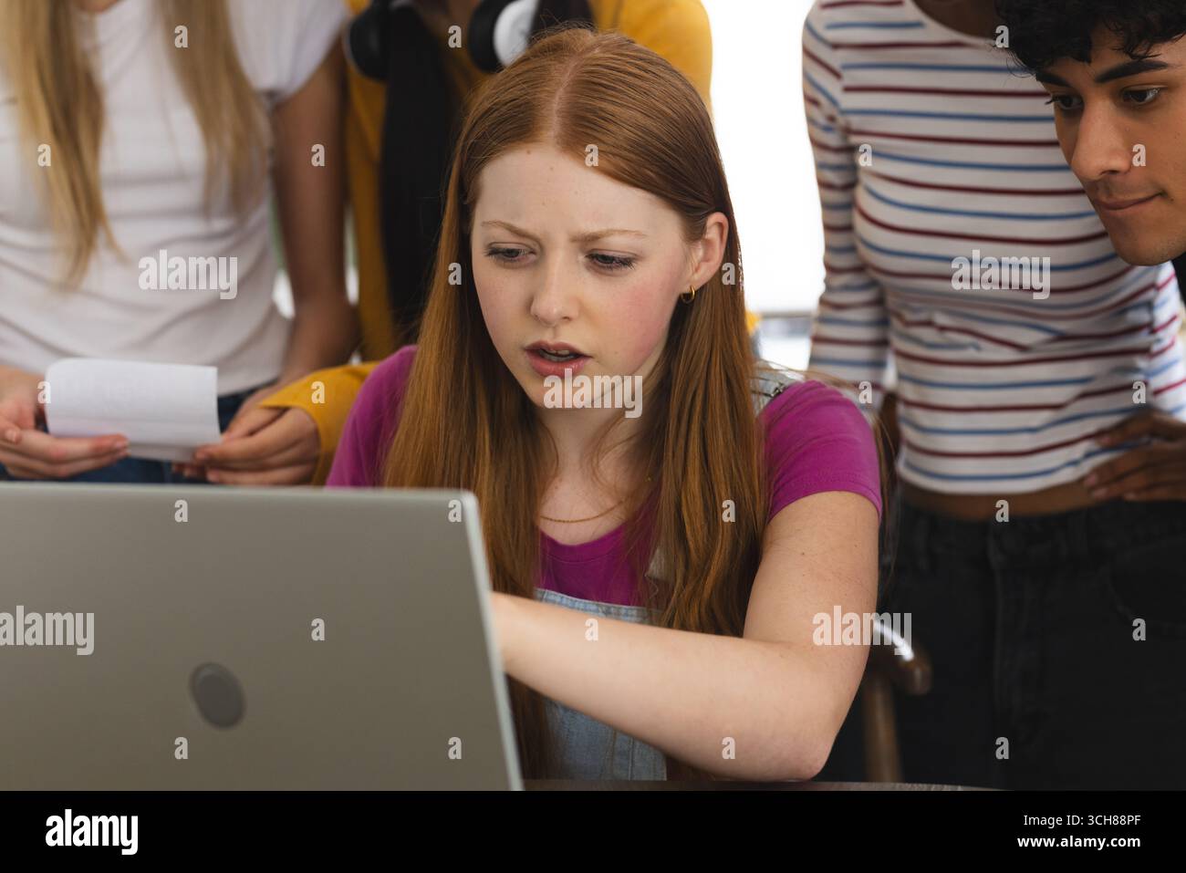 Adolescente se concentrant sur un ordinateur portable avec des amis, collaborant sur un projet scolaire Banque D'Images