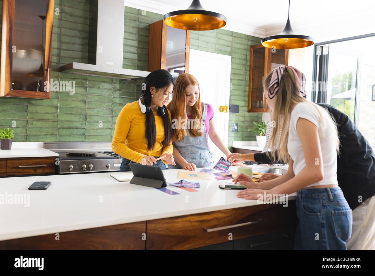Dans la cuisine moderne, des amis adolescents collaborent sur un projet créatif, partageant des idées avec enthousiasme Banque D'Images