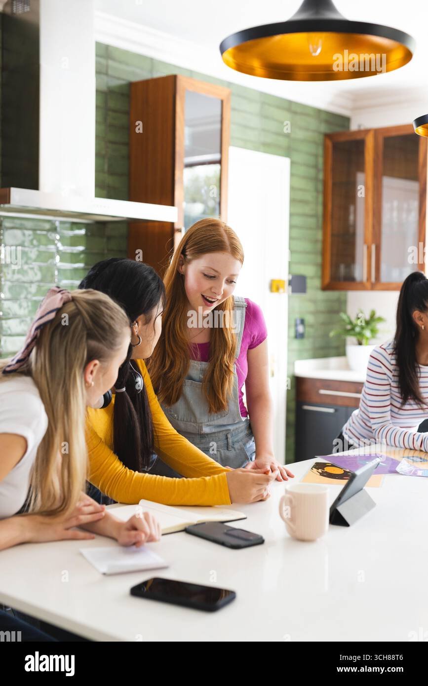 Des adolescentes collaborent sur un projet scolaire à la maison, en utilisant une tablette et des notes Banque D'Images