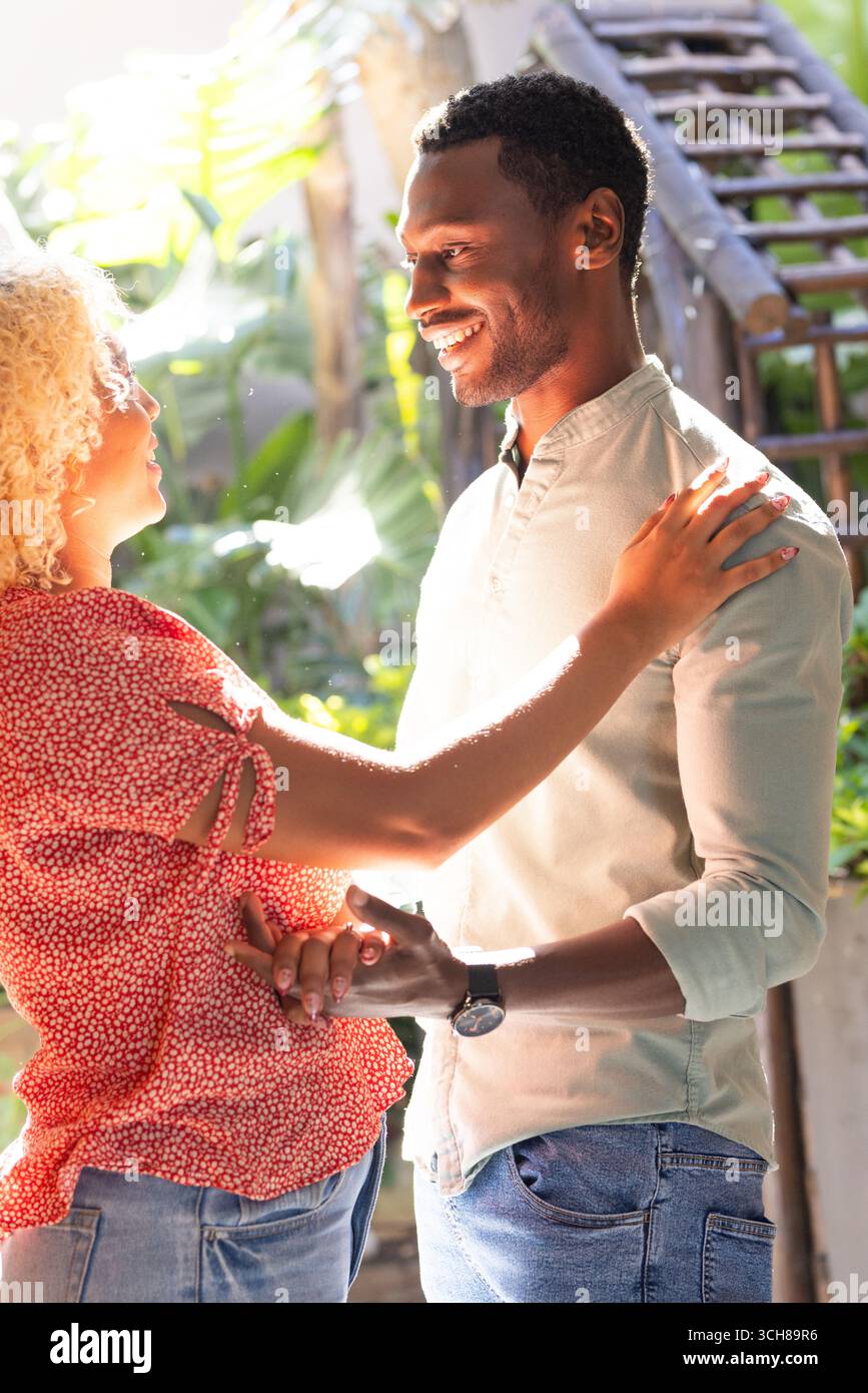 Amis souriants appréciant la conversation et le rire à l'extérieur dans le cadre ensoleillé du jardin Banque D'Images
