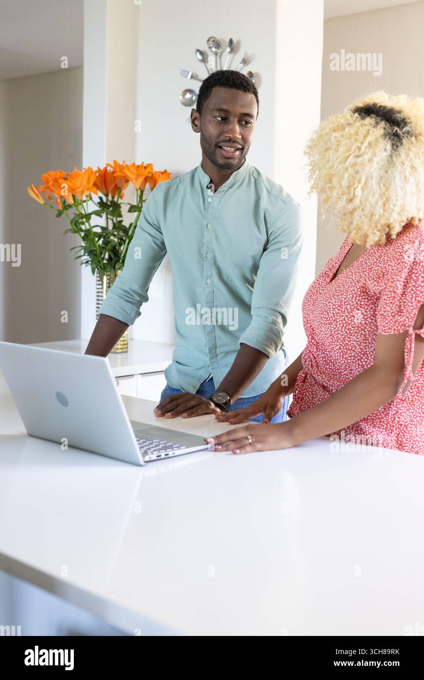 Amis collaborant sur ordinateur portable dans la cuisine moderne, discutant des idées de projet Banque D'Images