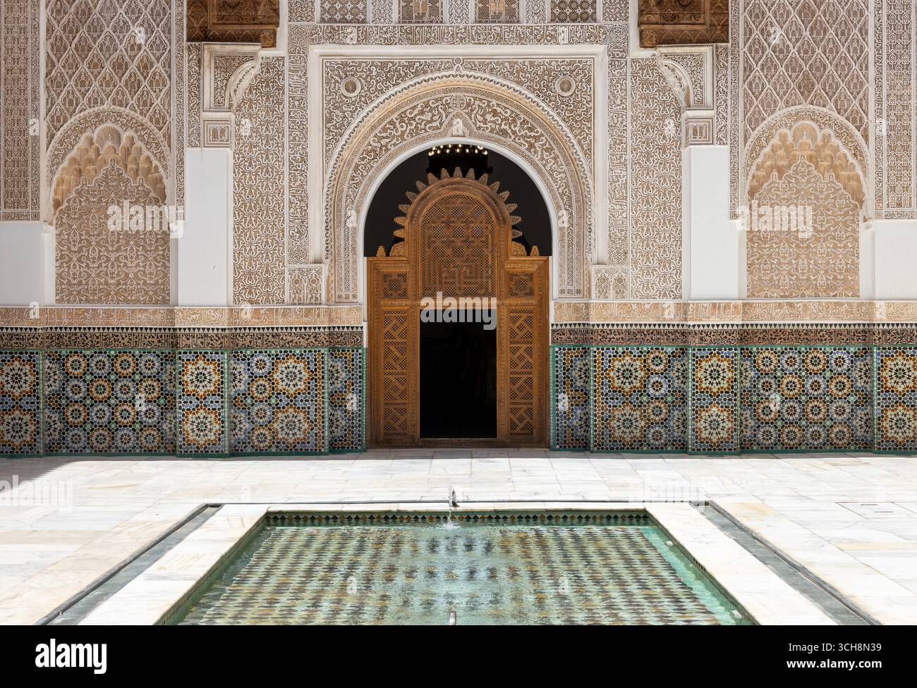 Stuc sculpté et frise de cèdre avec calligraphie arabe et petites fenêtres cintrées sur le mur de la cour de Ben Youssef Madrasa (Medersa Ben Youssef) Banque D'Images