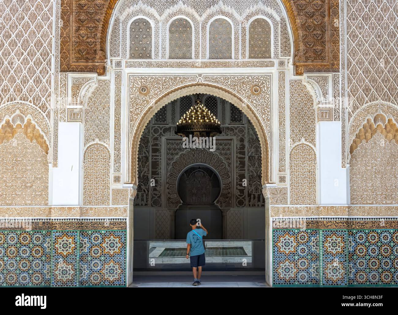 Stuc sculpté et frise de cèdre avec calligraphie arabe et petites fenêtres cintrées sur le mur de la cour de Ben Youssef Madrasa (Medersa Ben Youssef) Banque D'Images