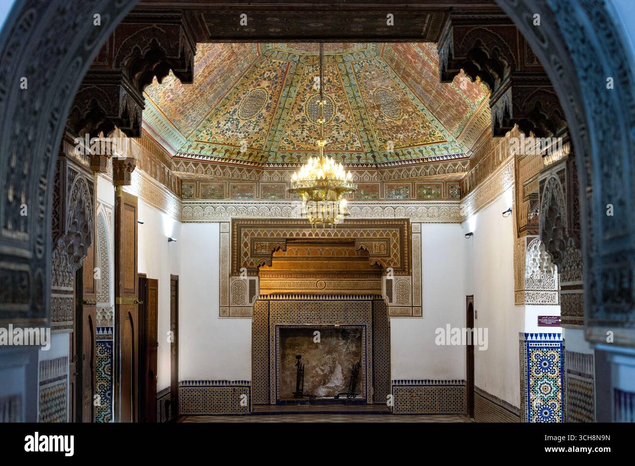 Salle de réception ornée avec plafond en cèdre peint, lustre et cheminée carrelée à l'intérieur du Palais Bahia (Palais Bahia), Marrakech, Maroc. Banque D'Images