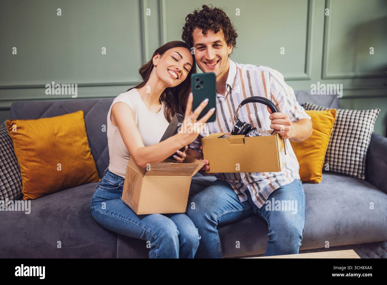 Couple adulte déballage leurs colis livrés à domicile. Ils prennent selfie avec de nouveaux objets. Banque D'Images