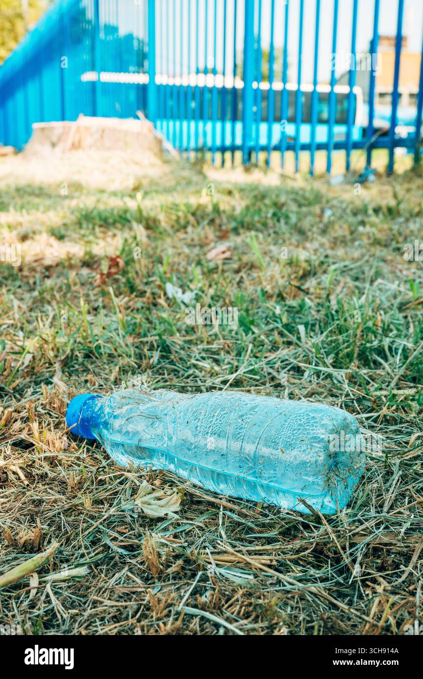 Bouteille d'eau en plastique jetée sur l'herbe sèche, soulignant la pollution, les déchets et l'impact environnemental. Mise au point sélective. Banque D'Images