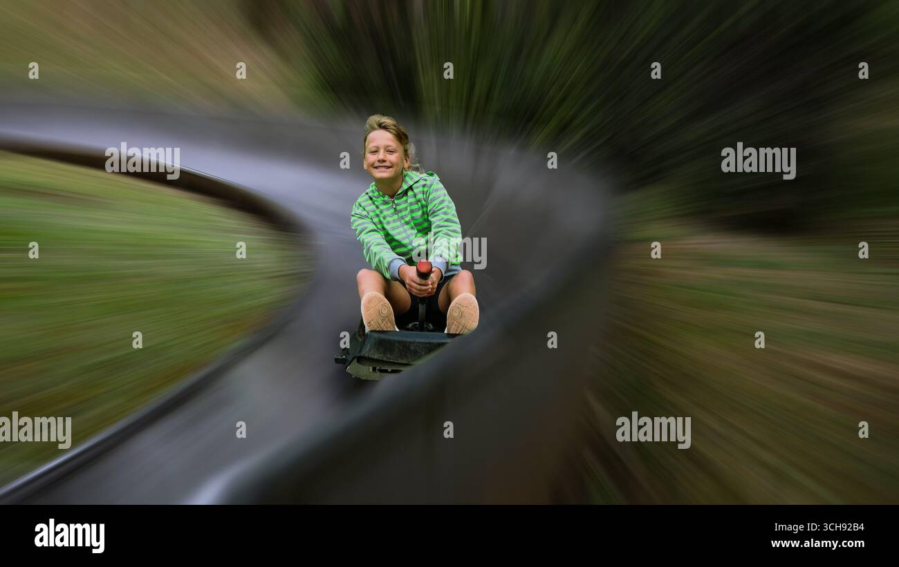 Enfant s'amusant descendant sur une montagne russe dans un flou de vitesse et d'excitation. Banque D'Images