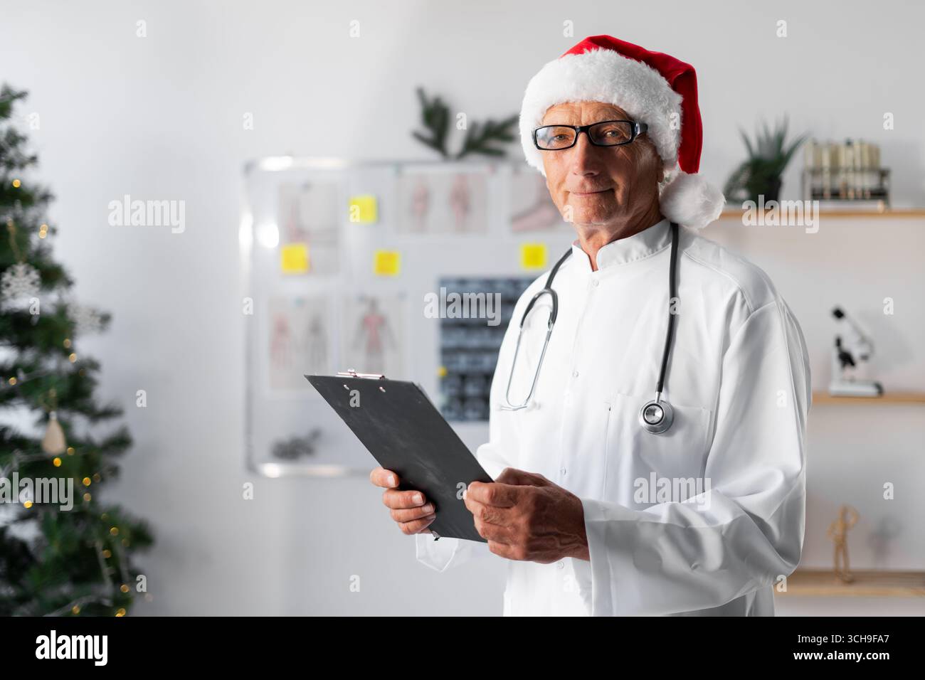 Médecin senior âgé à santa Hat travaillant dans la clinique sur le quart de la veille de noël. Copier l'espace Banque D'Images
