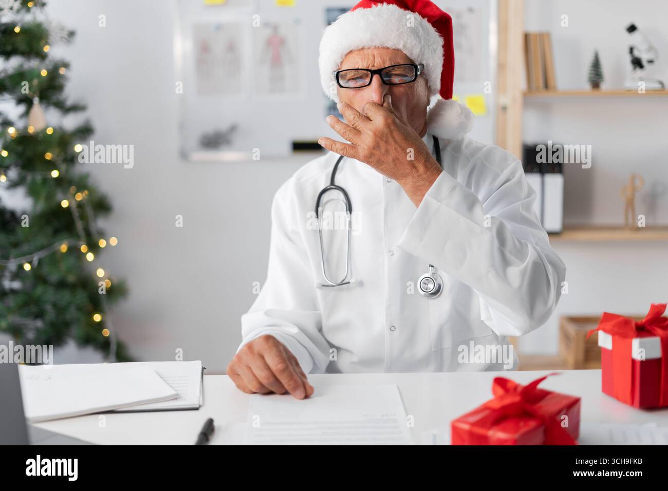 Médecin âgé senior dans le chapeau de Père Noël sur le quart de la veille de noël pressant le nez avec les doigts, avec l'expression de dégoût. copier l'espace Banque D'Images