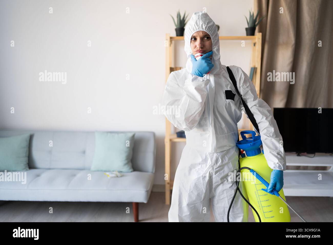 Exterminateur féminin du service de lutte antiparasitaire travaillant à l'intérieur de la maison avec bouteille de pulvérisateur pensant au problème à la maison. copier l'espace Banque D'Images