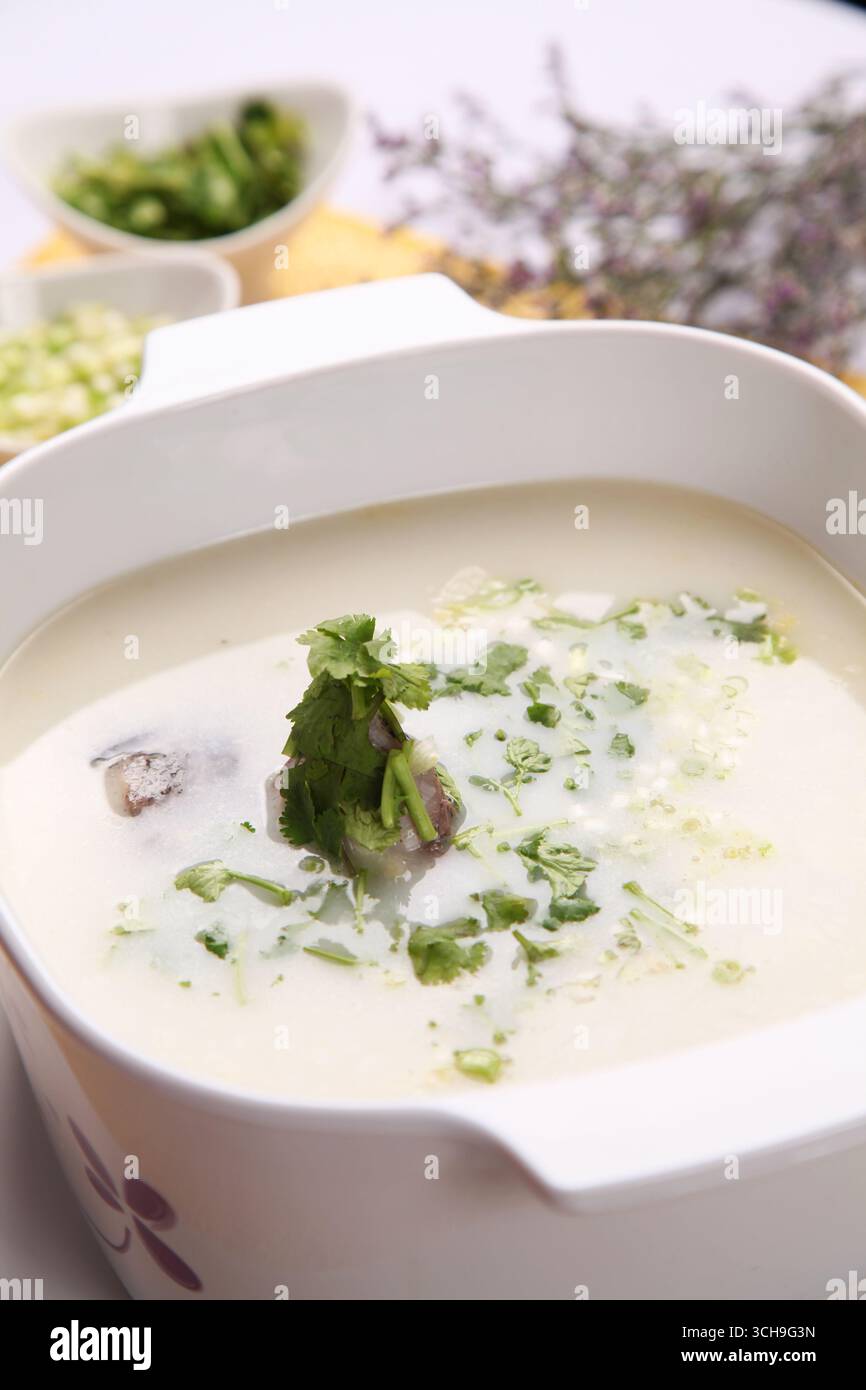 Soupe de poisson laiteux à la coriandre dans une casserole en céramique Banque D'Images