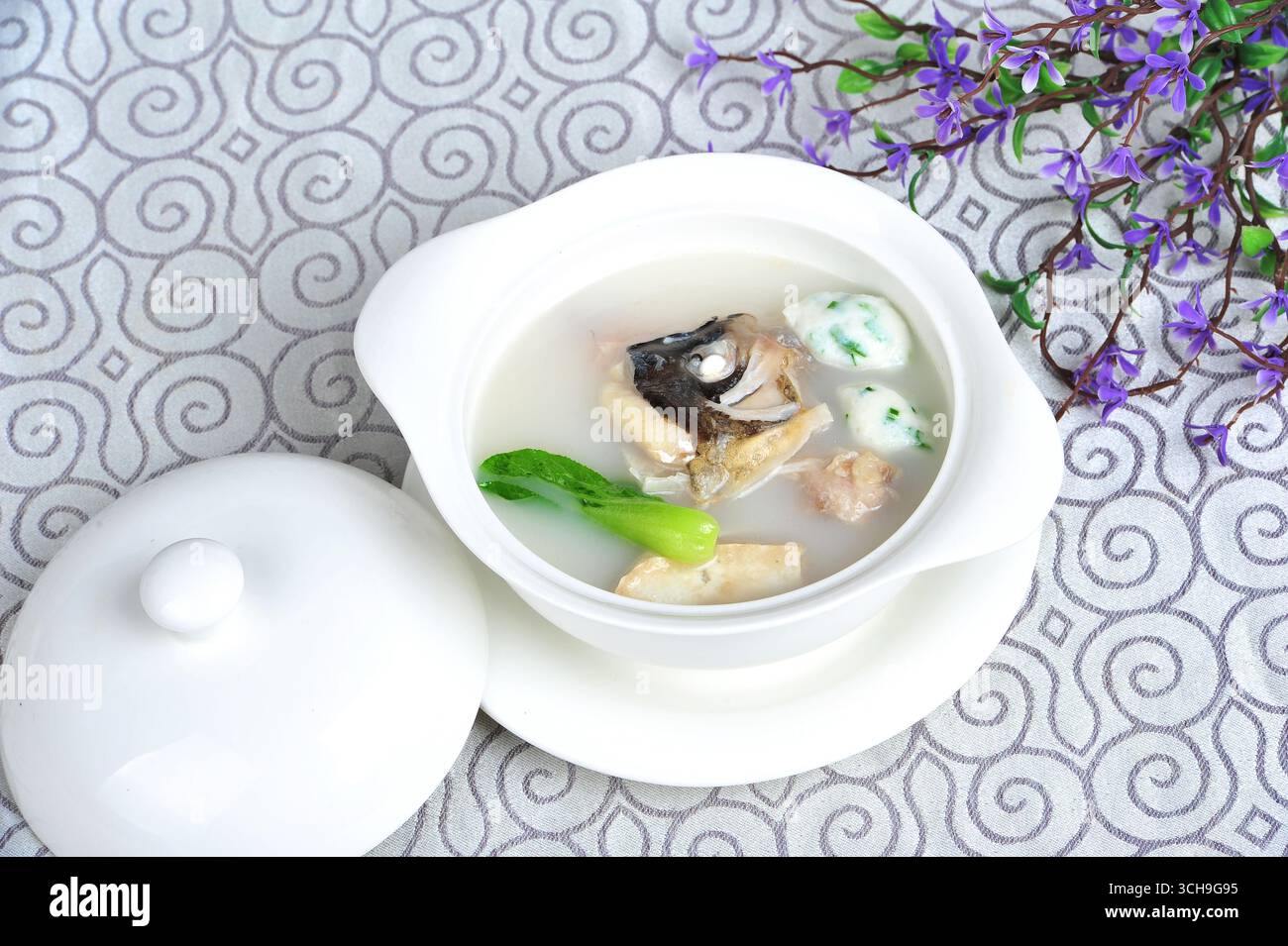 Soupe de tête de poisson laiteux avec des verts dans un bol en porcelaine Banque D'Images