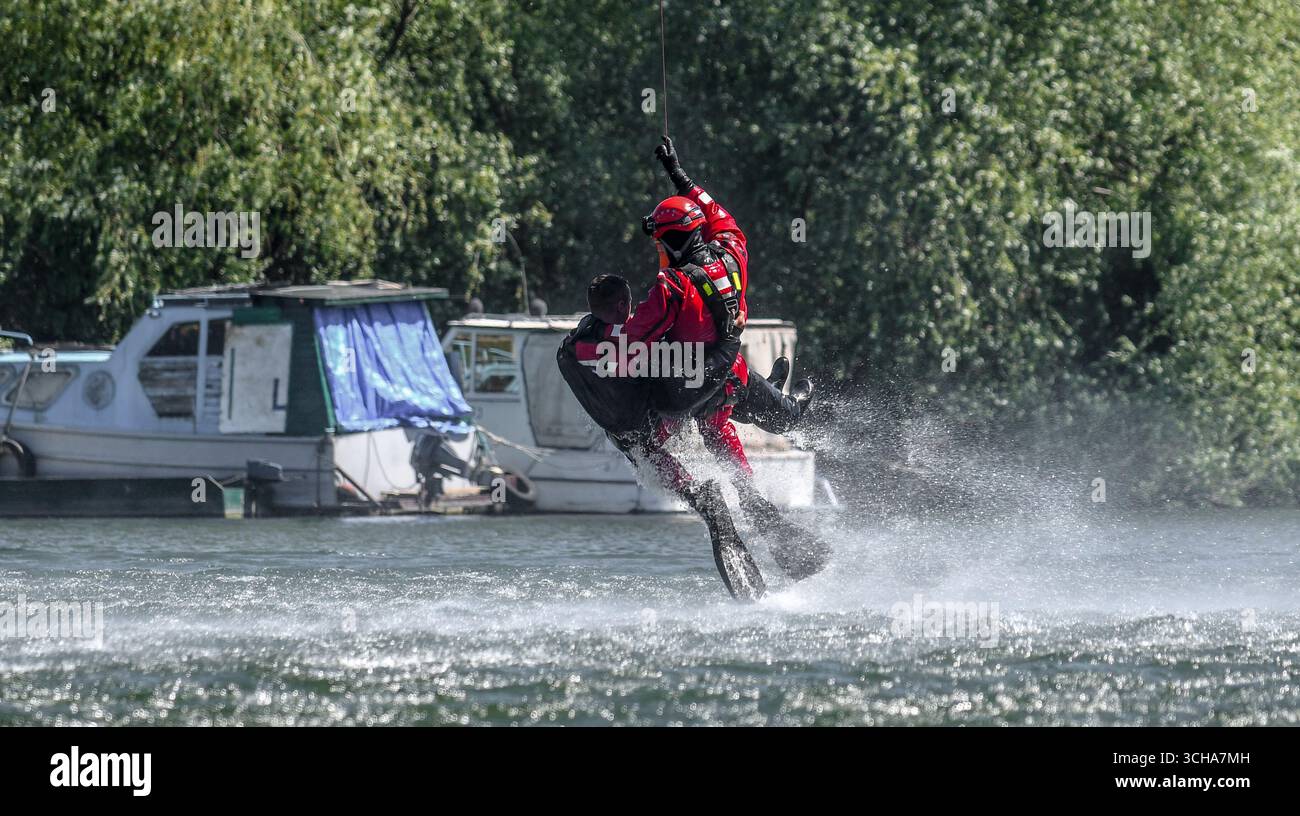 Sauveteur suspendu au câble d'un hélicoptère transportant un homme hors de l'eau pendant une opération de sauvetage. Banque D'Images
