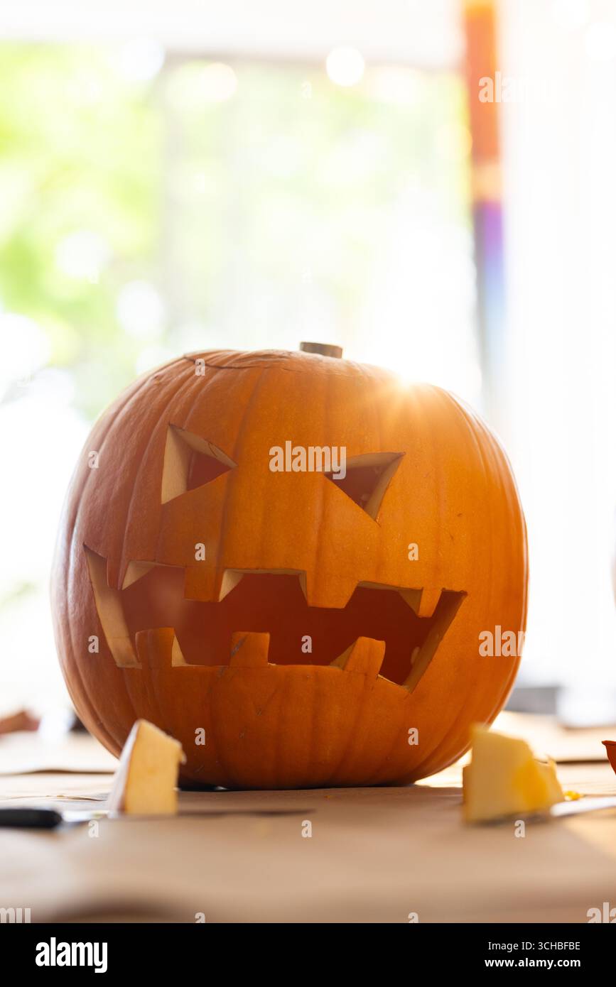 Citrouille sculptée brillante à la lumière du soleil sur la table, prête pour la célébration d'Halloween, à la maison. automne, décoration, jack-o'-lanterne, festif, effrayant, saisonnier Banque D'Images