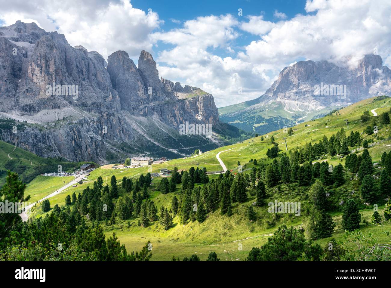 Paysage alpin spectaculaire au col de Gardena dans les Dolomites avec des pics rocheux, des prairies verdoyantes, des forêts de conifères et des routes sinueuses sous SK d'été nuageux Banque D'Images