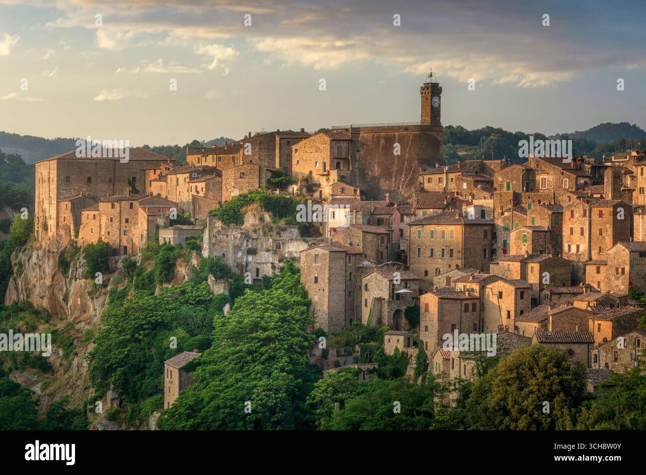 Village médiéval de Sorano en Toscane avec d'anciens bâtiments en pierre, murs de forteresse et tour de l'horloge perché de façon spectaculaire sur les falaises de tuf à l'heure dorée. Banque D'Images Village médiéval de Sorano en Toscane avec d'anciens bâtiments en pierre, murs de forteresse et tour de l'horloge perché de façon spectaculaire sur les falaises de tuf à l'heure dorée. Banque D'Images