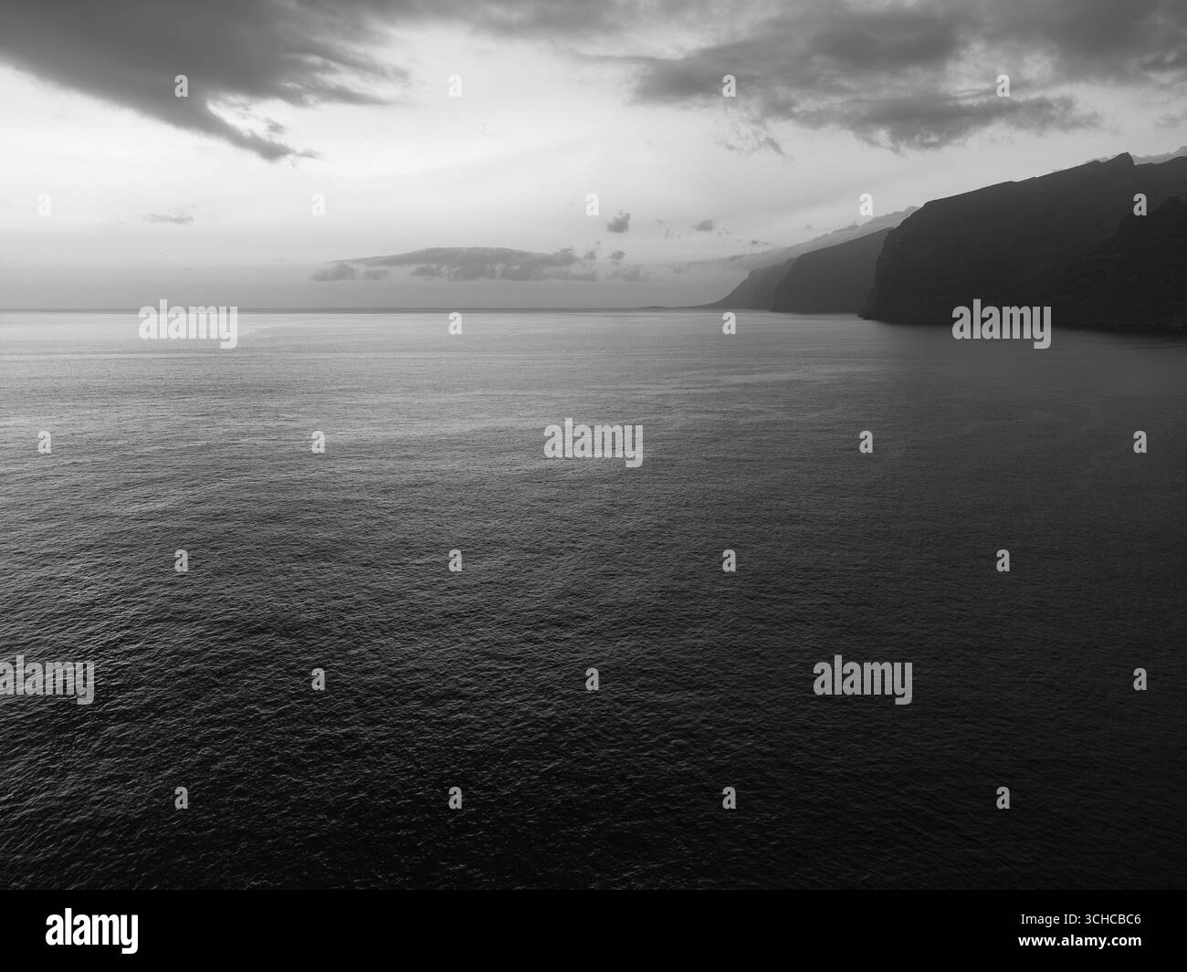Coucher de soleil sur l'océan Atlantique près de Tenerife, Espagne, projetant des teintes chaudes dans le ciel. Le soleil est partiellement obscurci par des nuages lointains Banque D'Images