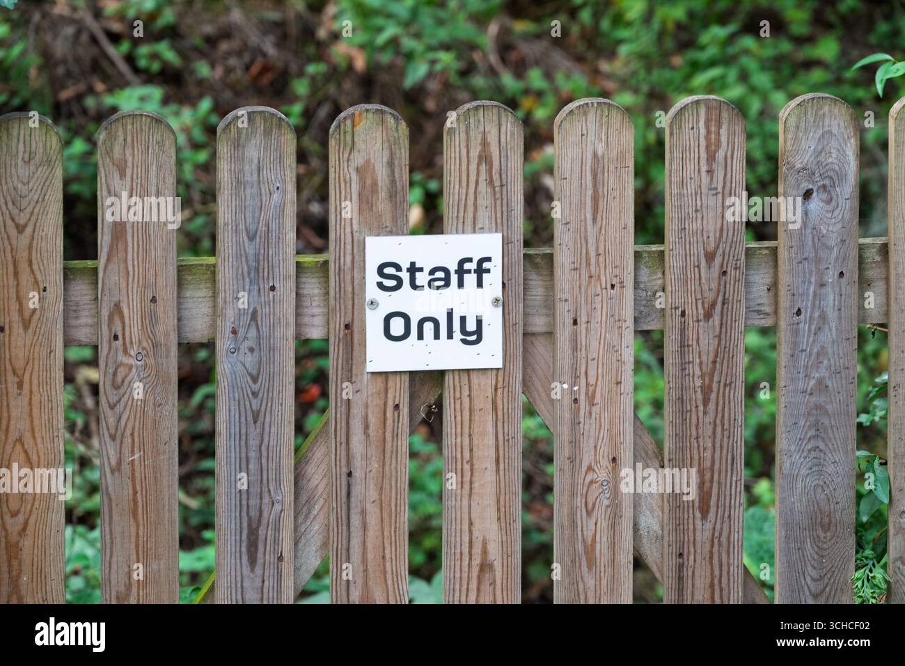 Une clôture en bois altérée se dresse comme une barrière, marquée d'un panneau « personnel seulement ». Banque D'Images