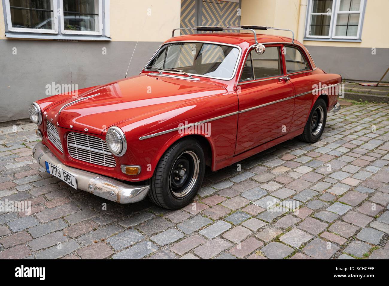 Voiture vintage rouge classique garée sur une rue pavée en face d'un bâtiment traditionnel Banque D'Images
