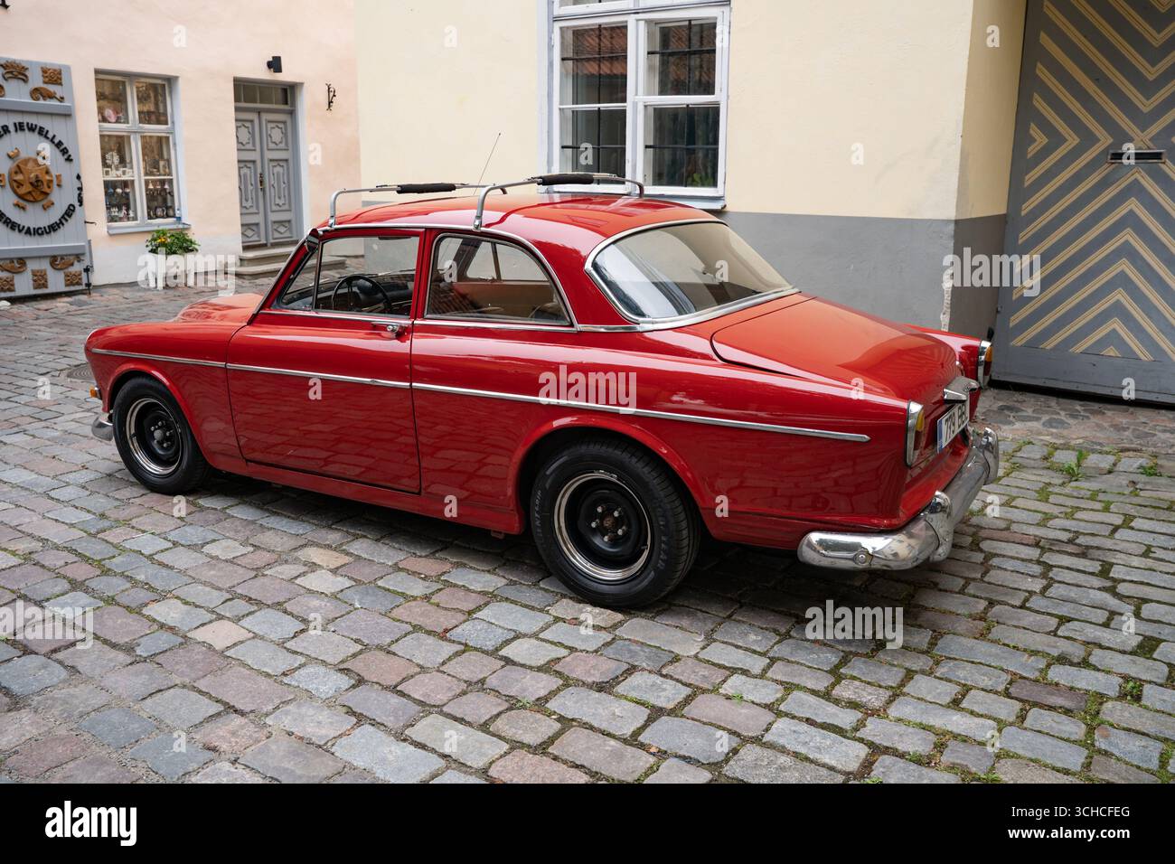 Voiture vintage rouge classique garée sur une rue pavée dans la place historique de la ville estonienne Banque D'Images