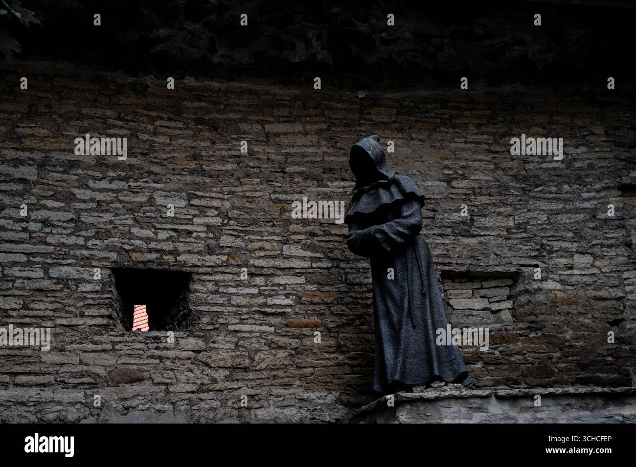 Statue de moine médiévale contre un mur de pierre antique avec une petite fenêtre à Tallinn, Estonie Banque D'Images