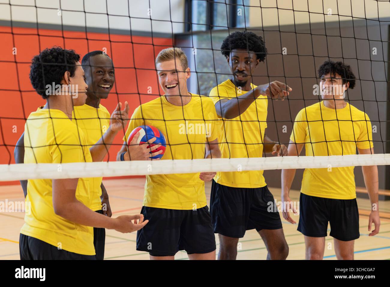 Divers coéquipiers masculins en maillots debout sur le terrain discutant de stratégie tenant le volleyball par filet. Athlétisme, travail d'équipe, camaraderie, sport, fitness, c Banque D'Images Divers coéquipiers masculins en maillots debout sur le terrain discutant de stratégie tenant le volleyball par filet. Athlétisme, travail d'équipe, camaraderie, sport, fitness, c Banque D'Images