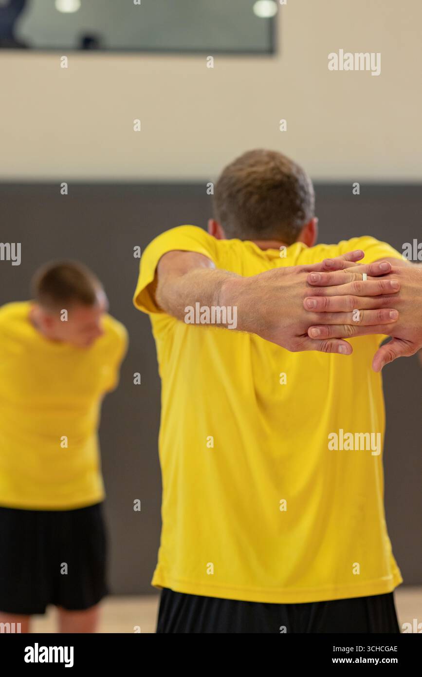 Partenaires d'entraînement masculin s'étirant en studio portant des chemises jaunes et des shorts noirs. Athlètes, fitness, exercice, entraînement, bien-être, flexibilité, guérison Banque D'Images Partenaires d'entraînement masculin s'étirant en studio portant des chemises jaunes et des shorts noirs. Athlètes, fitness, exercice, entraînement, bien-être, flexibilité, guérison Banque D'Images