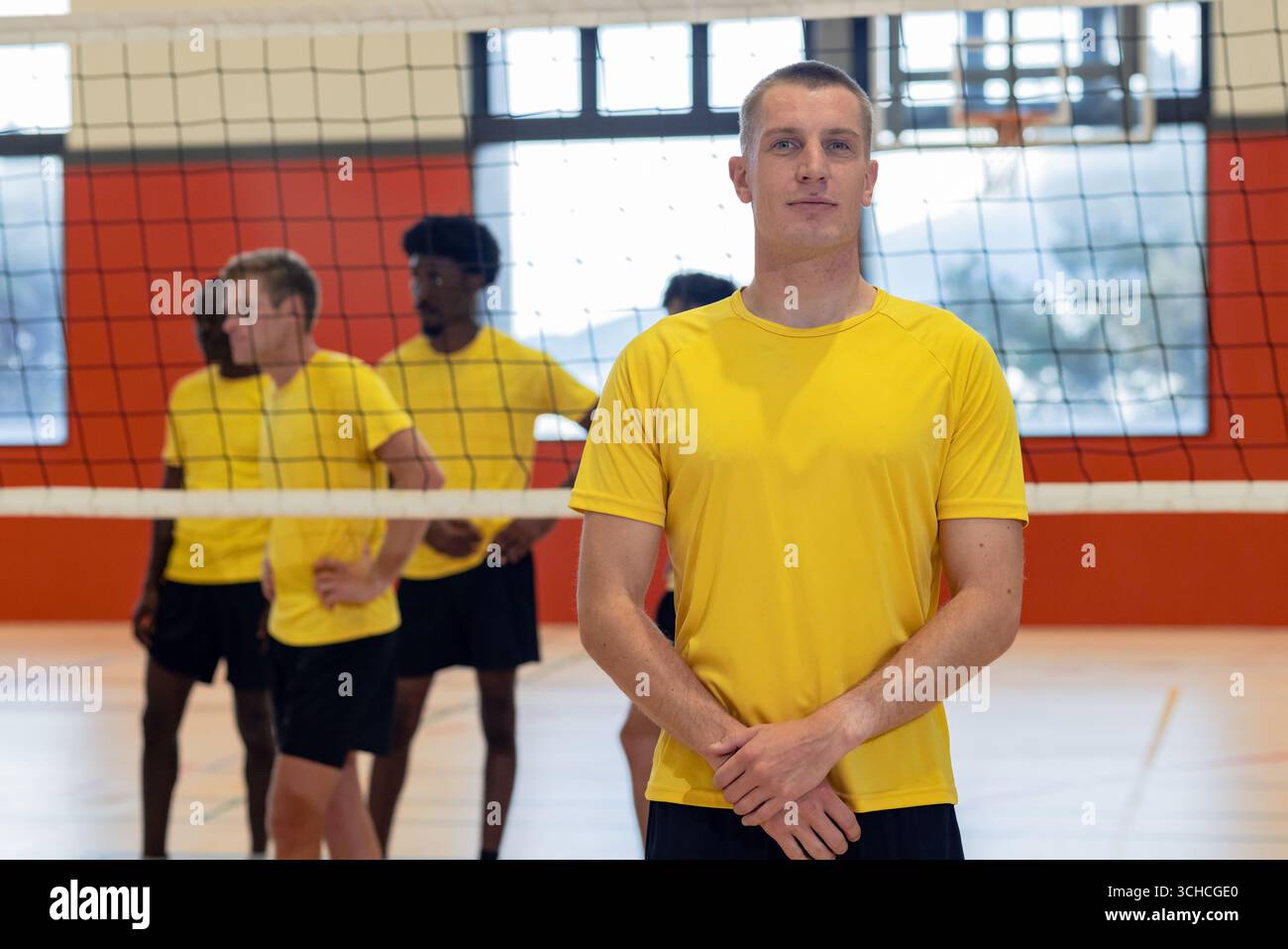Divers coéquipiers masculins en maillots jaunes et shorts debout sur un terrain de volley-ball dans la salle de gym avec filet. Athlètes, travail d'équipe, entraînement, fitness, sports, compe Banque D'Images Divers coéquipiers masculins en maillots jaunes et shorts debout sur un terrain de volley-ball dans la salle de gym avec filet. Athlètes, travail d'équipe, entraînement, fitness, sports, compe Banque D'Images