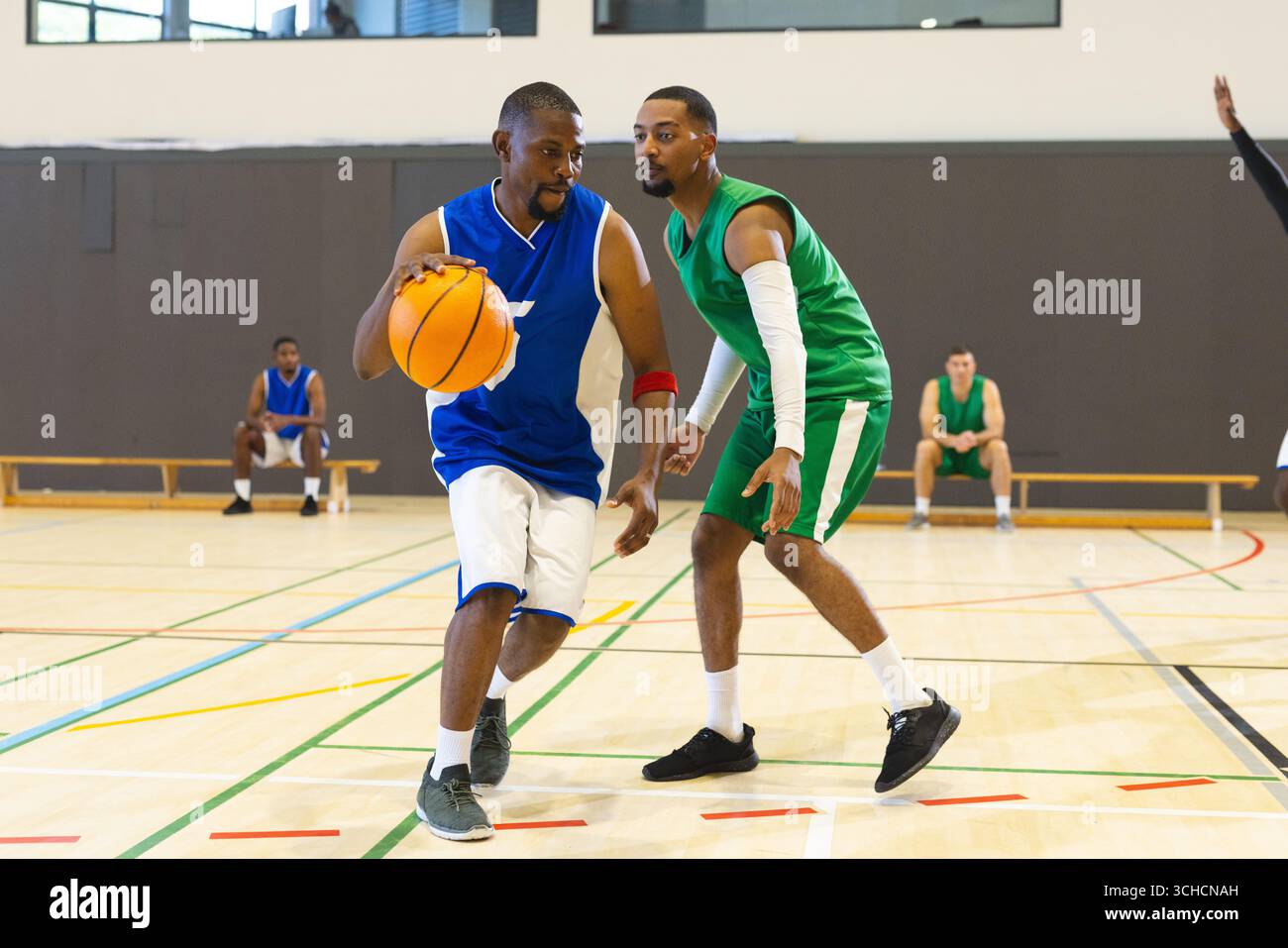 Homme afro-américain dribble basket-ball en uniforme bleu sur le terrain de gymnastique avec les lignes du terrain, espace de copie. Athlètes, compétition, sport, entraînement, physique, Banque D'Images