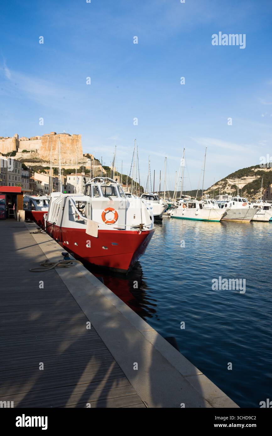 Le port de Bonifacio sur la côte sud de la Corse, France. Beau bateau debout sur l'eau de mer calme dans la lumière du soleil du matin. Banque D'Images