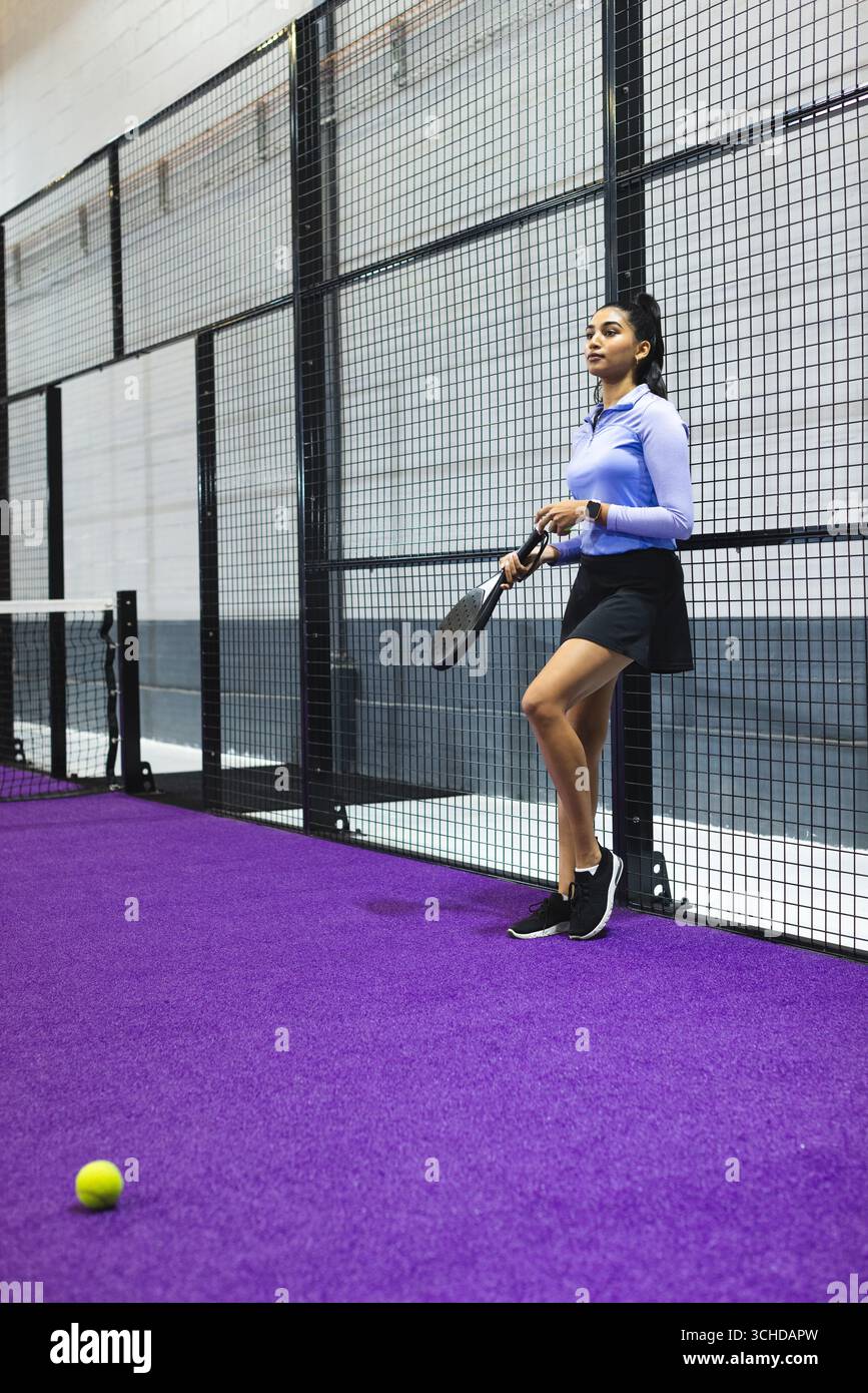 Athlète féminine avec raquette padel et smartwatch sur le terrain violet par balle jaune, espace copie Banque D'Images