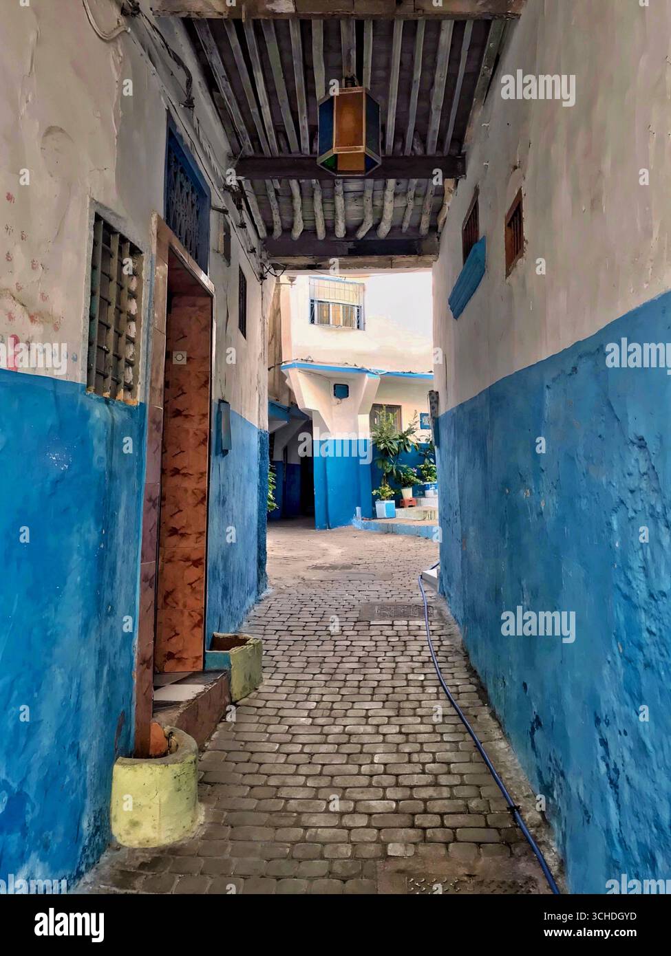Étroite ruelle pavée dans la Kasbah de Tanger, avec des murs bleus et blancs, des poutres en bois et une lanterne – Tanger Maroc 29 Nov 2019. Banque D'Images