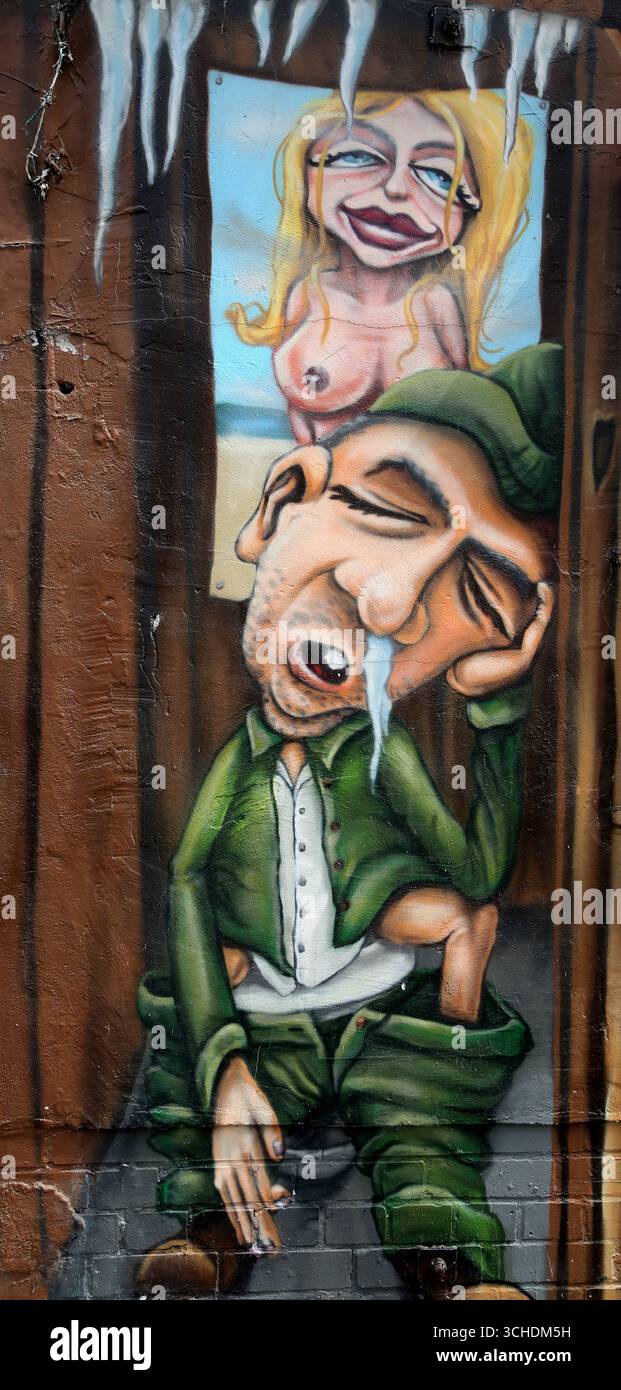 Des graffitis vibrants ornent le mur de Berlin, représentant une scène humoristique d'un homme dans une situation comique Banque D'Images