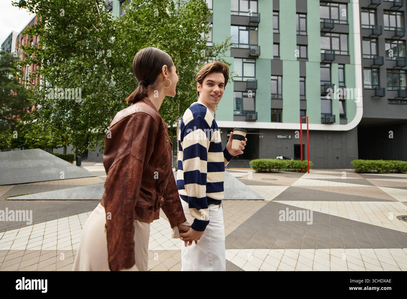 Un couple aimant aime se promener ensemble, se tenir la main et partager des sourires dans un parc urbain moderne. Banque D'Images