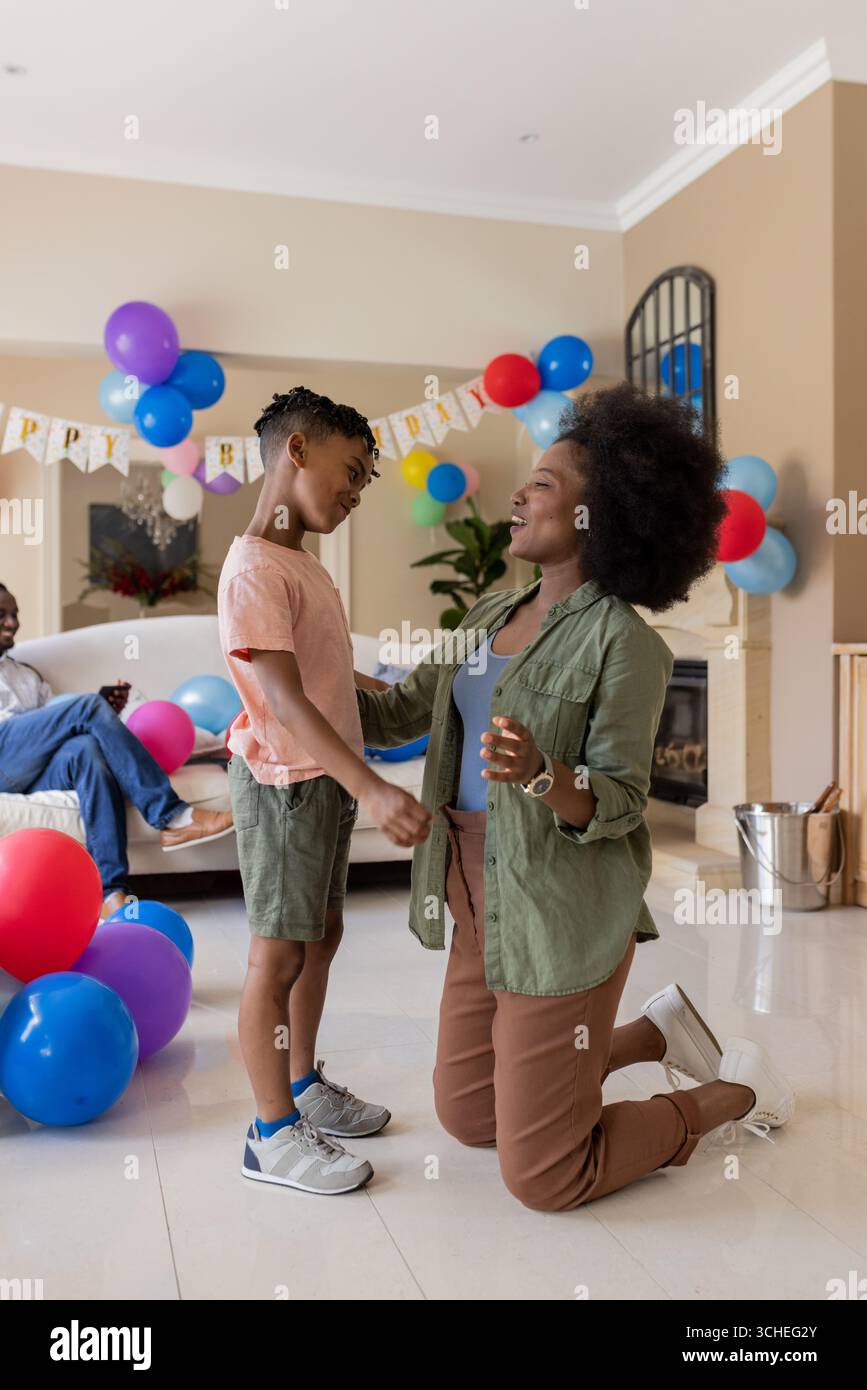 Célébrer l'anniversaire à la maison, mère afro-américaine et enfant avec des ballons souriants Banque D'Images