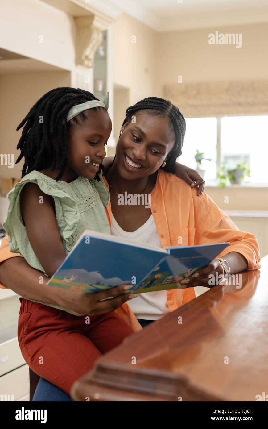 Mère et fille lisant le livre d'histoires ensemble à la maison, partageant des moments joyeux Banque D'Images Mère et fille lisant le livre d'histoires ensemble à la maison, partageant des moments joyeux Banque D'Images