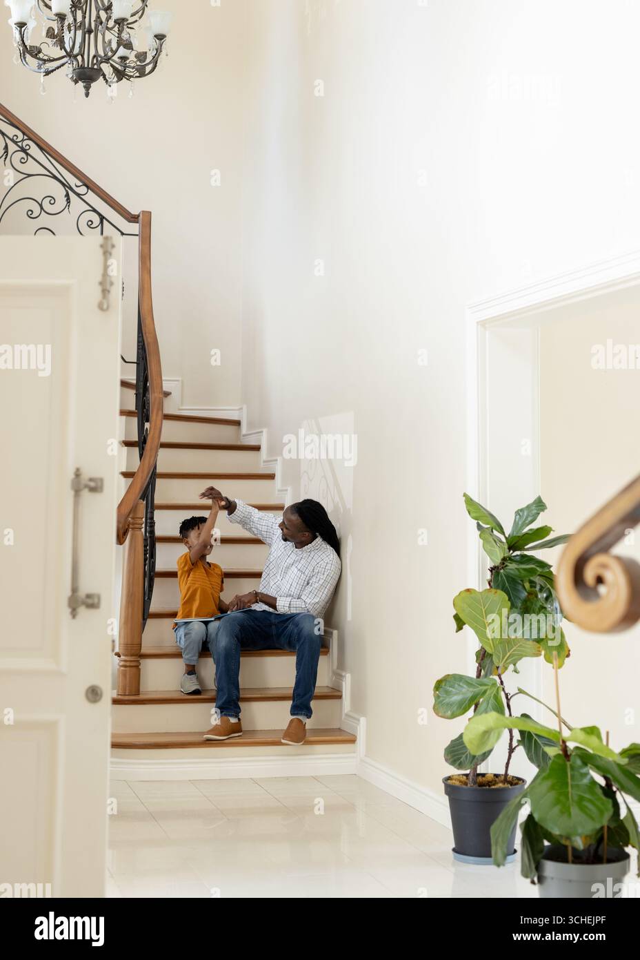 Père et fils assis dans les escaliers, jouant et liant à la maison, espace de copie Banque D'Images Père et fils assis dans les escaliers, jouant et liant à la maison, espace de copie Banque D'Images
