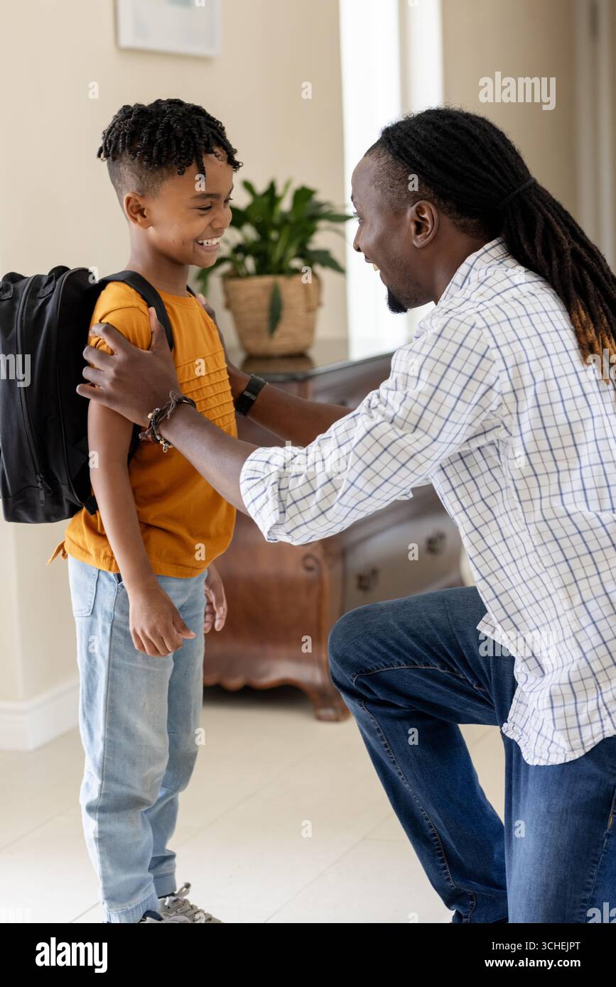 Père encourageant son fils avec un sac à dos, se préparant à l'école à la maison Banque D'Images Père encourageant son fils avec un sac à dos, se préparant à l'école à la maison Banque D'Images