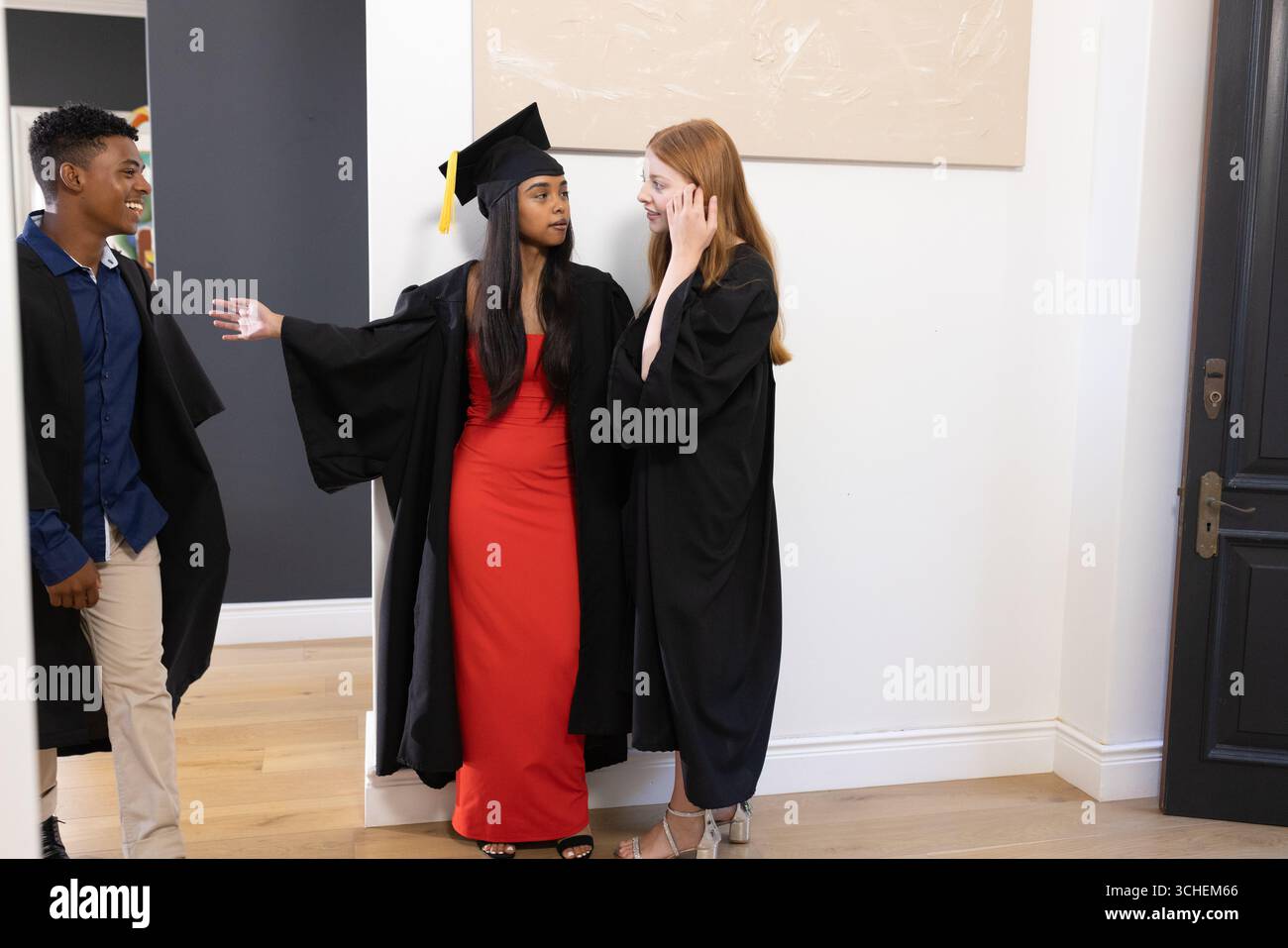 Étudiants diplômés en casquettes et robes célébrant ensemble dans le couloir Banque D'Images