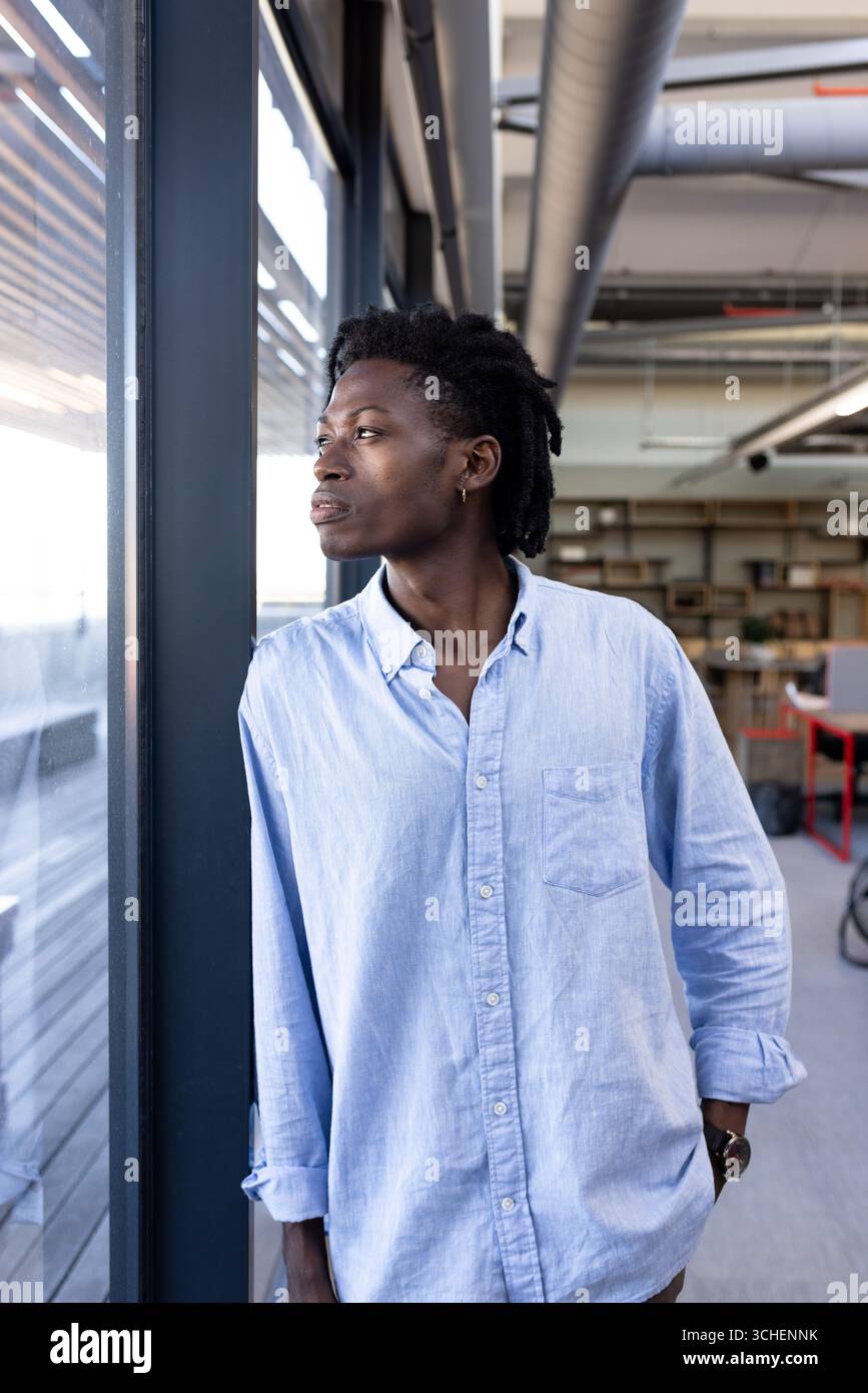 Professionnel confiant dans le bureau regardant par la fenêtre, envisageant de nouvelles opportunités Banque D'Images