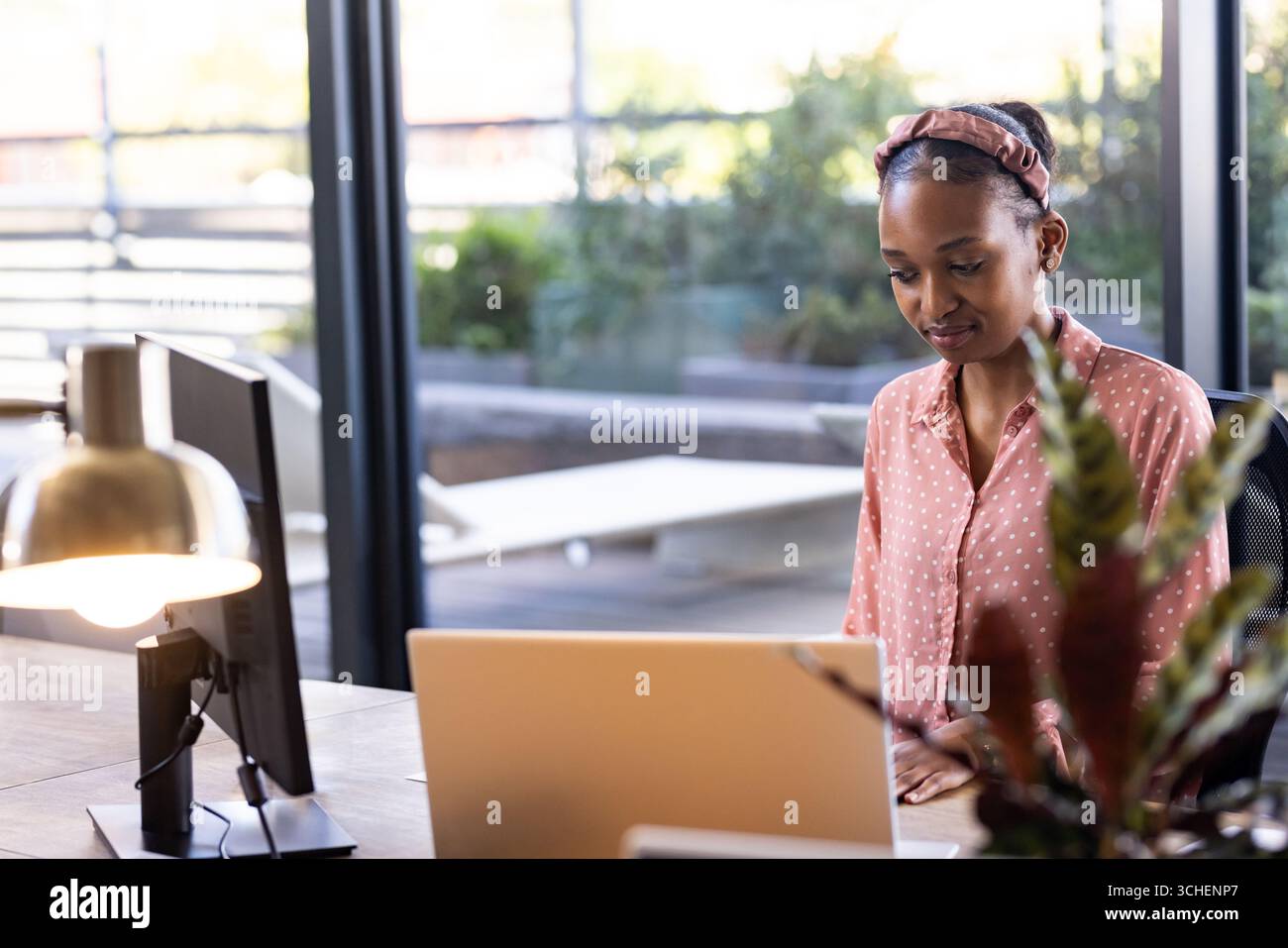 Femme afro-américaine travaillant sur ordinateur portable au bureau moderne, se concentrant sur la tâche, l'espace de copie Banque D'Images