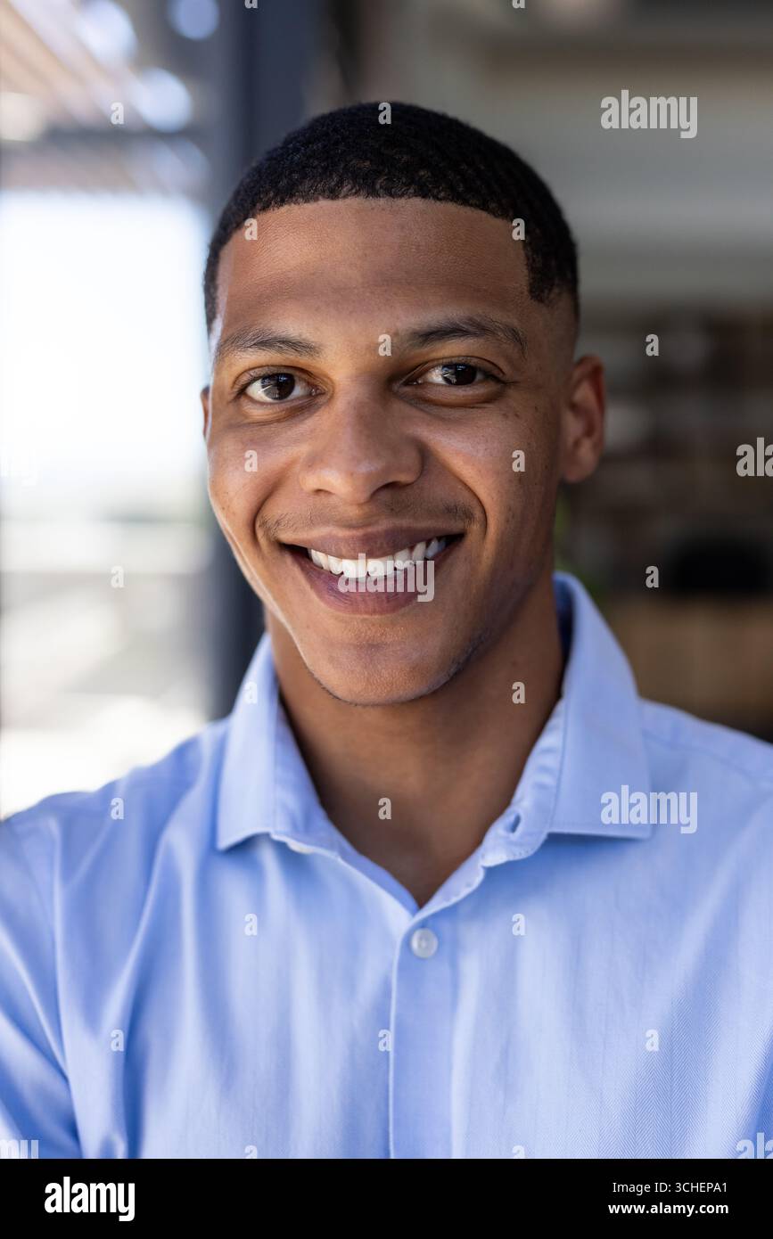 Au bureau, homme en chemise bleue souriant, regardant confiant Banque D'Images