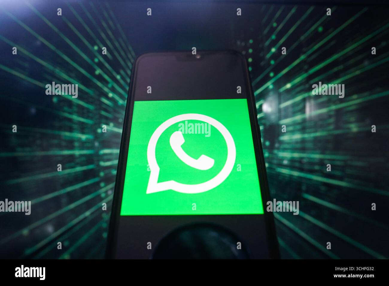 Dans cette illustration photo, un logo WhatsApp est affiché sur un smartphone avec des lignes de code sur le fond. Banque D'Images