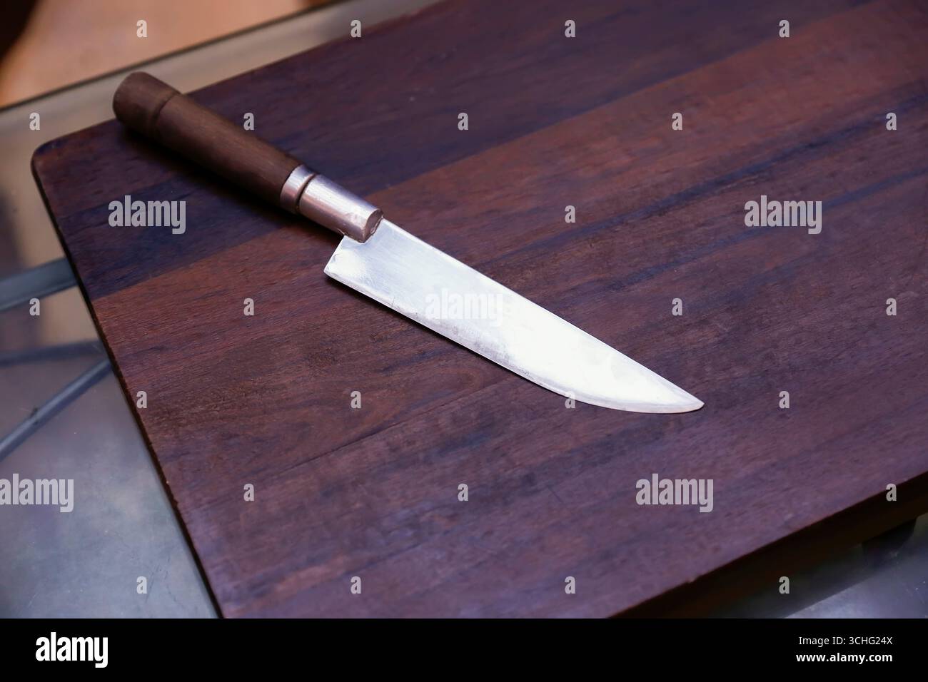 Couteau avec lame brillante sur comptoir en bois rustique, parfait pour une coupe précise et un réglage de cuisine chaleureux Banque D'Images