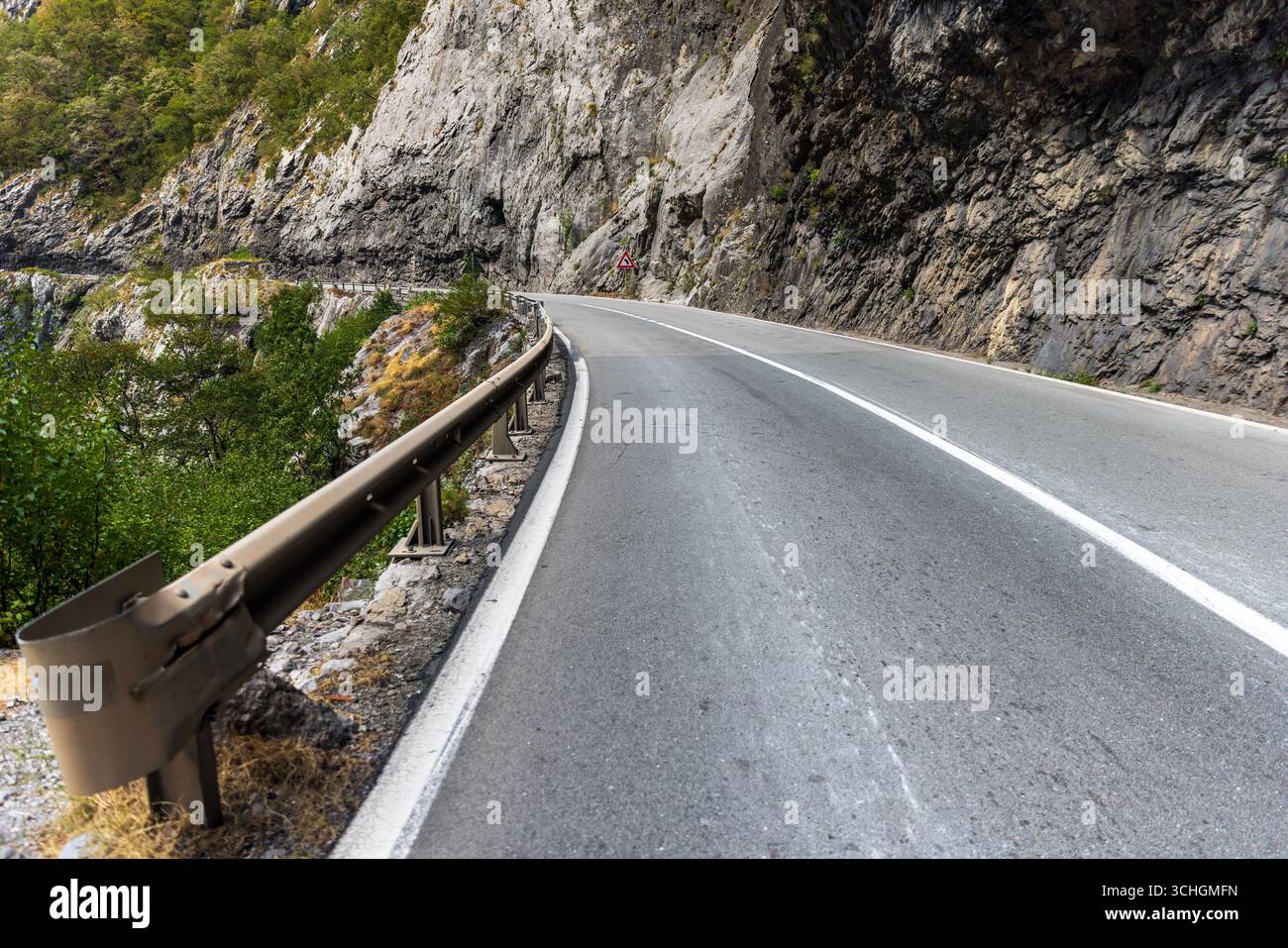 Vue panoramique d'un virage de route de montagne serré entouré de falaises rocheuses et de verdure, capturant parfaitement la beauté naturelle et l'aventure du tra en plein air Banque D'Images