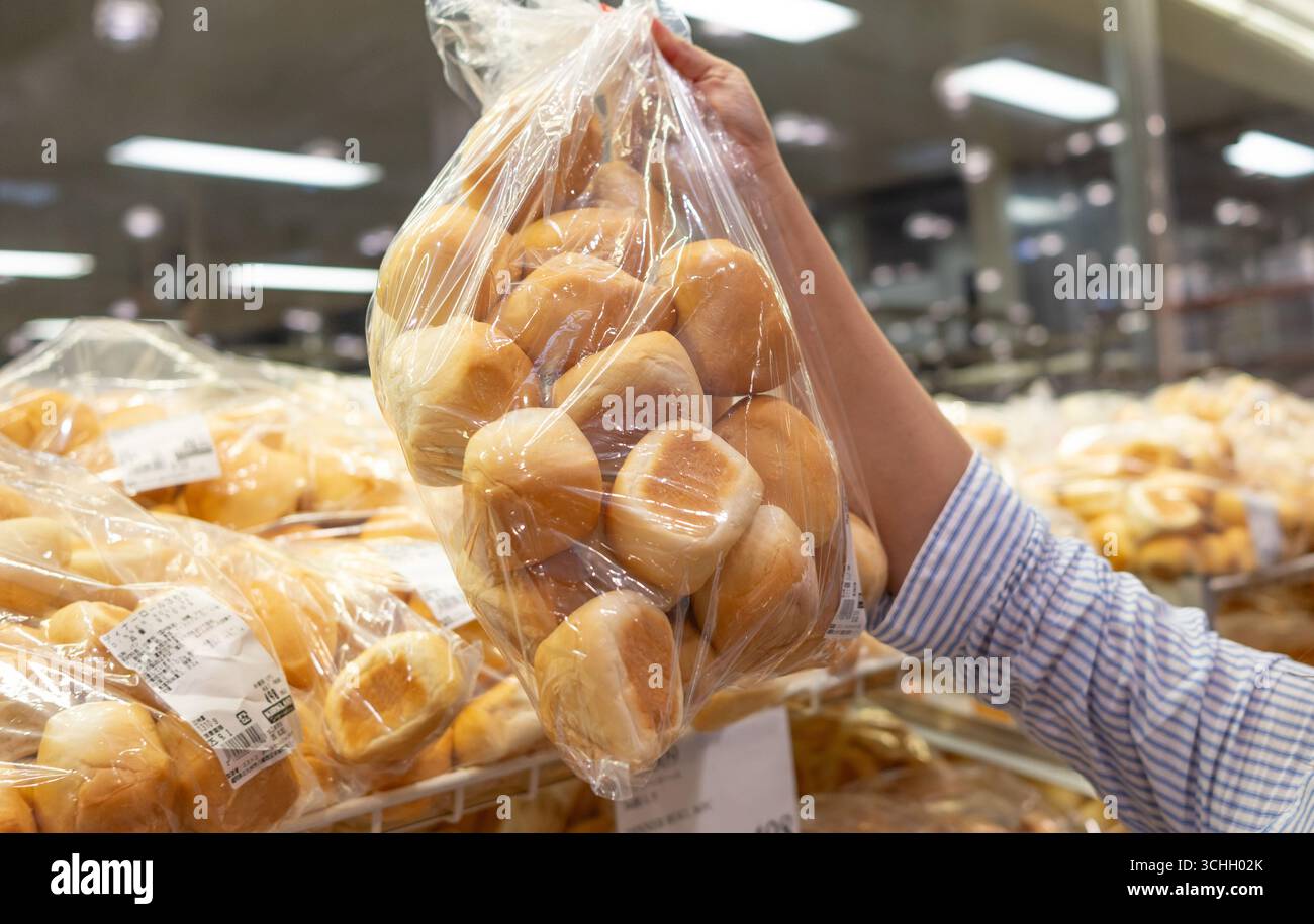 La main d'un client qui prend un sac de Costco Dinner Rolls sur l'étagère Banque D'Images