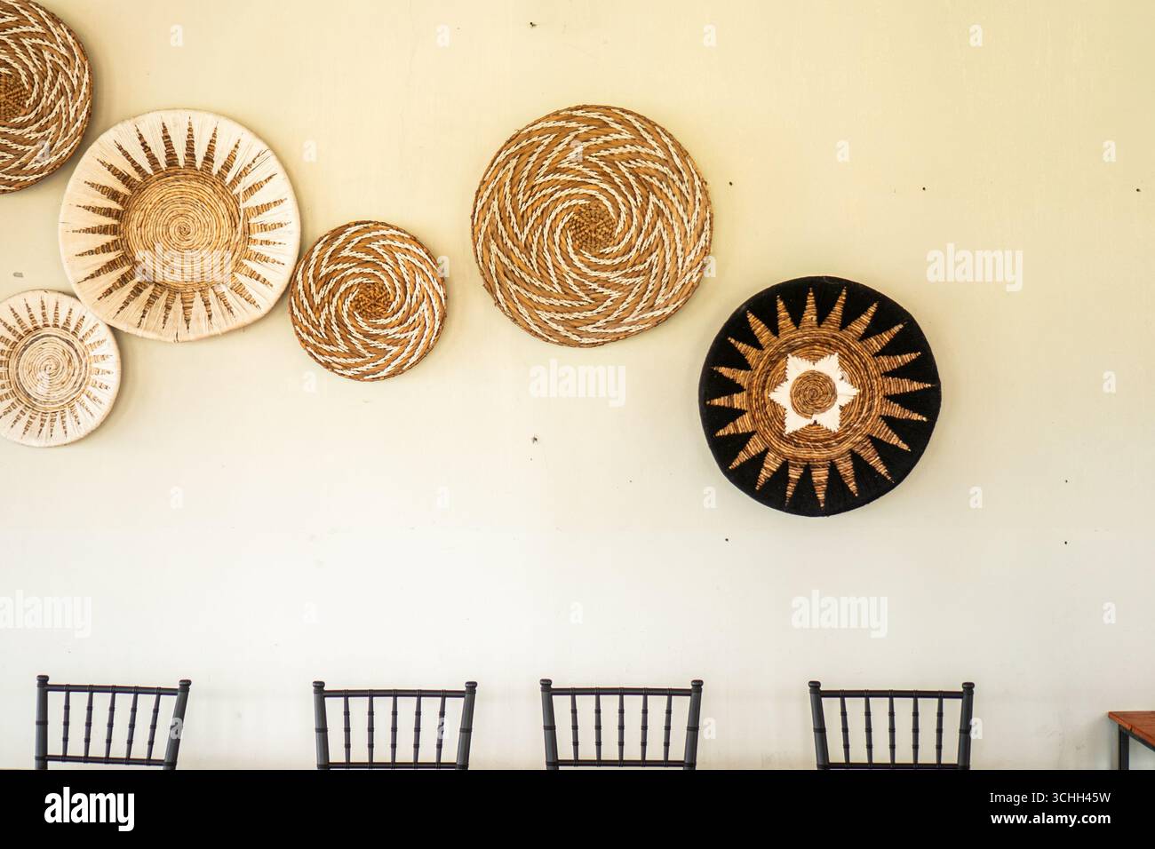 Paniers tissés faits à la main avec des motifs ethniques accrochés sur le mur blanc comme décoration intérieure de style bohème. Banque D'Images