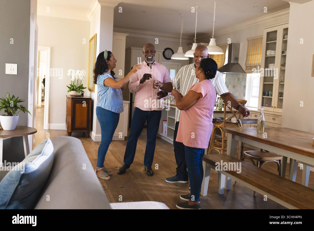 Aînés afro-américains célébrant avec des verres à champagne dans la cuisine familiale confortable Banque D'Images