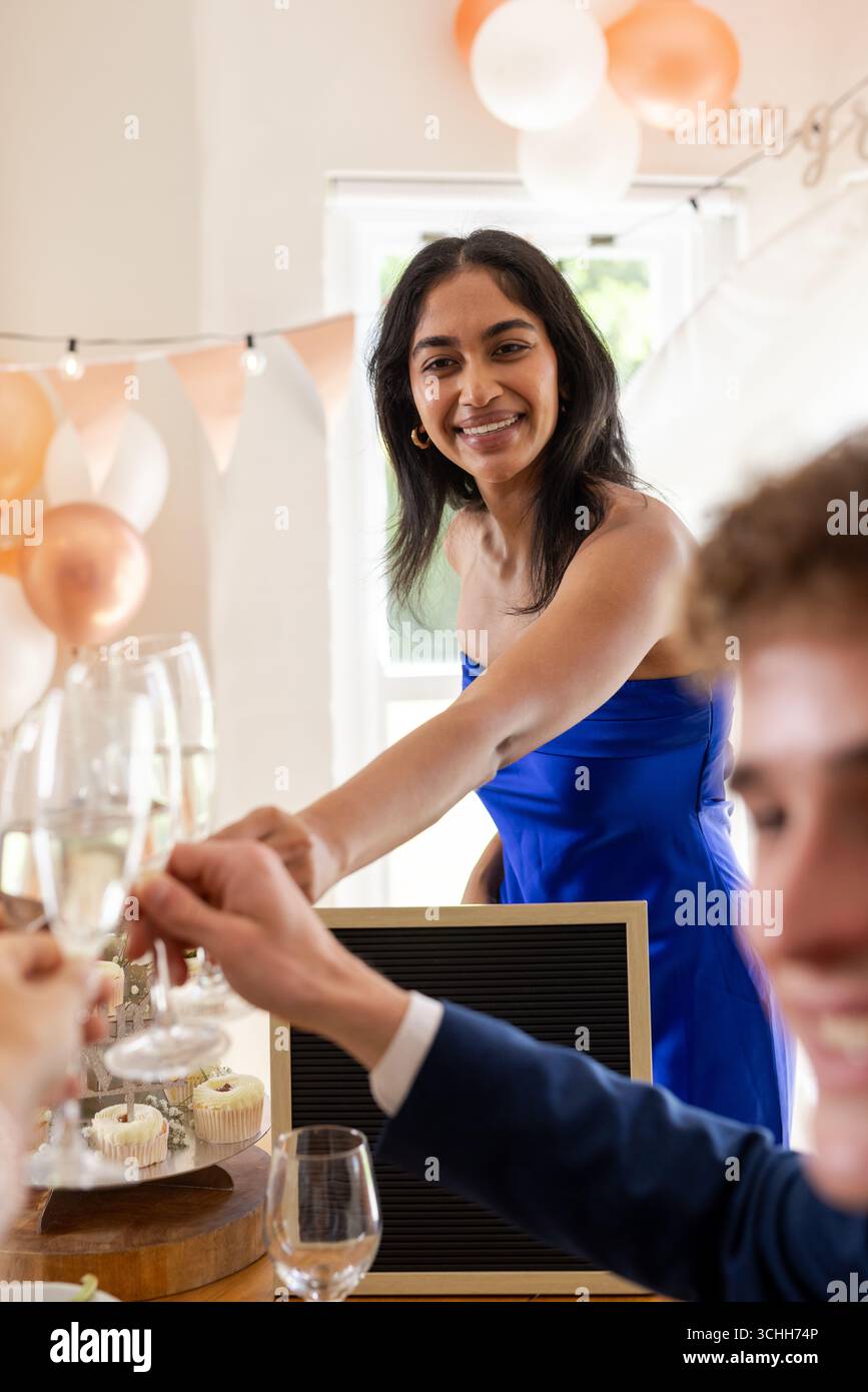 Femme souriante en robe bleue grillant avec des amis à la célébration de mariage Banque D'Images