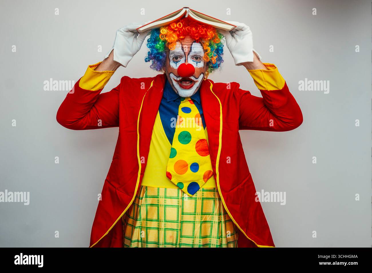 Clown couvrant la tête avec un livre Banque D'Images
